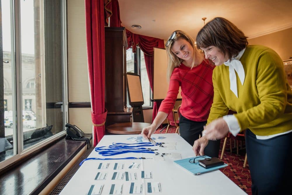 women collect passes from conference table