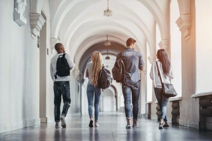 four students walk down hallway